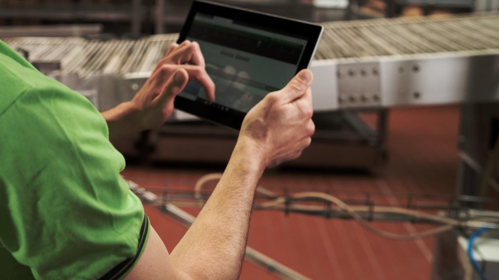 Ein Biotec Klute Techniker in grünem Polo-Hemd hält ein Tablet